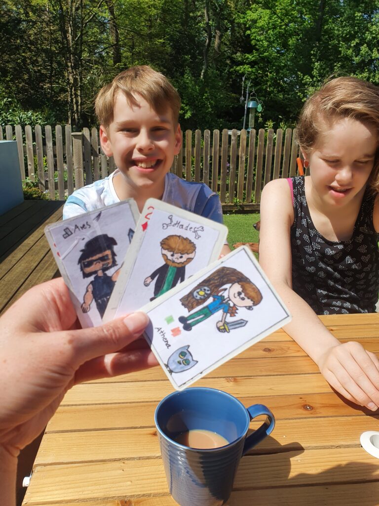 2 teenagers playing a card game they created in a sunny back garden. One of many half-term activities they got up to.