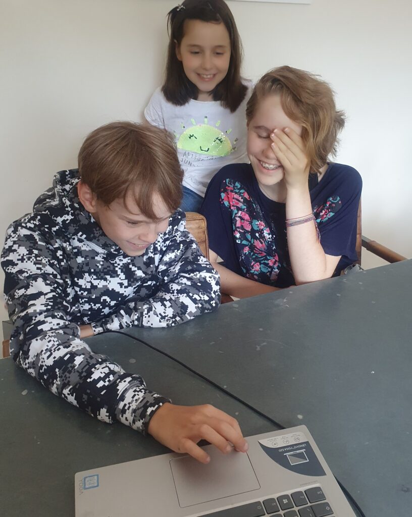The same teens plus a younger girl having fun playing on online escape room on their laptop as one of many half-term activities they got up too.